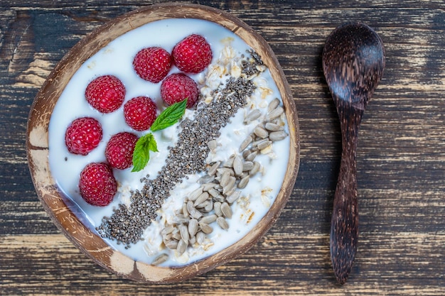 Smoothie w misce kokosowej z malinami, płatkami owsianymi, nasionami słonecznika i nasionami chia na śniadanie z bliska Koncepcja zdrowego odżywiania pożywieniem Widok z góry