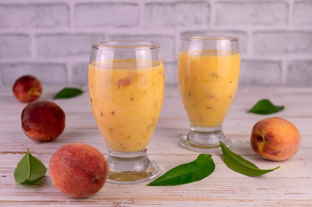 Smoothie ze świeżych organicznych brzoskwiń w szklankach whisky na białym tle.