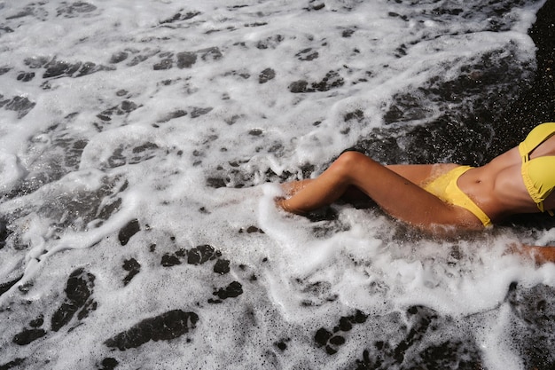 Smukłe seksowne ciało dziewczyny w stroju kąpielowym leżącej na plaży nad morzem