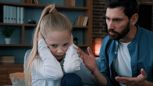 Smutna córeczka czuje stres zakrywający uszy, ignorując krzyk zły zirytowany tata krzyczący na dziewczynę