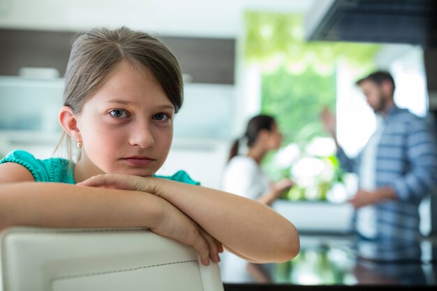 Smutna Dziewczyna Opiera Się Na Krześle, Podczas Gdy Rodzice Się Kłócą