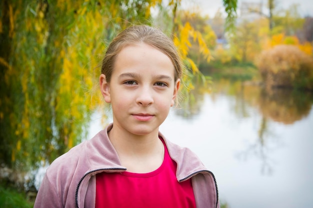 Smutna dziewczyna stoi w pobliżu jeziora w jesiennym parku