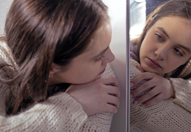 Zdjęcie smutna dziewczyna w depresji patrzy na swoje odbicie w lustrze