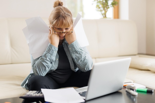 Smutna kaukaska freelancerka w średnim wieku, zmęczona pracą w nadgodzinach online, siedząca w domu w th