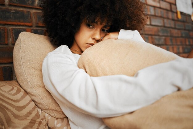 Smutna, przygnębiona i samotna czarna kobieta z problemami ze zdrowiem psychicznym przytulająca poduszkę w domu Portret afrykańskiej kobiety afro w depresji stres i lęk uczucie nieszczęśliwe życie samotnie w domu