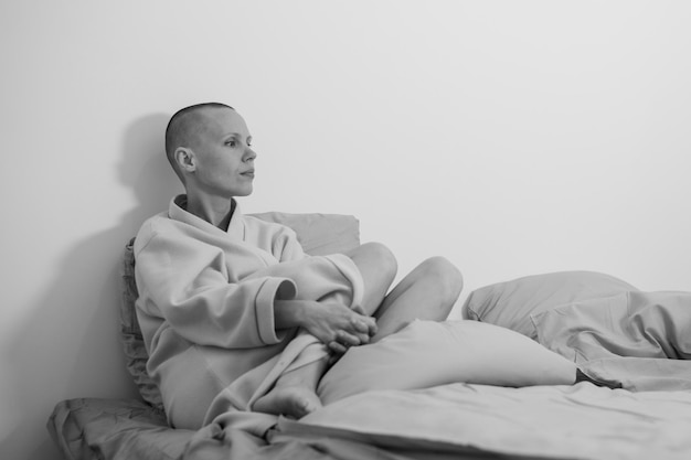 Smutna przygnębiona kobieta łysa na łóżku Oczekiwanie na operację chemioterapia stresujący czas Czarno-białe zdjęcie