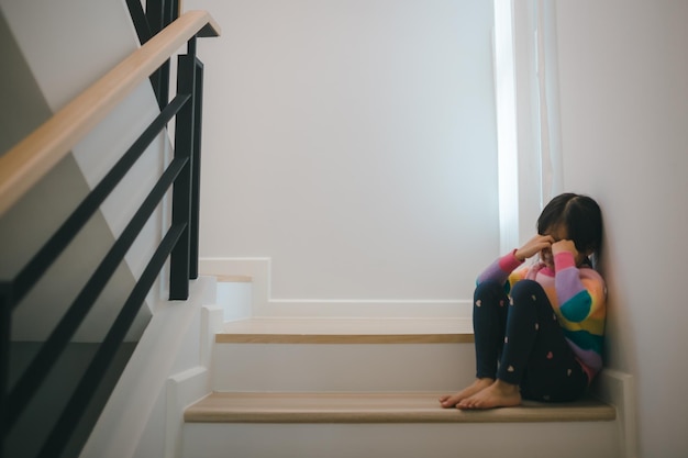 Smutne dziecko tego ojca i matki kłóci się o negatywną koncepcję rodzinną, małe dziewczynki siedzą i płaczą na schodach