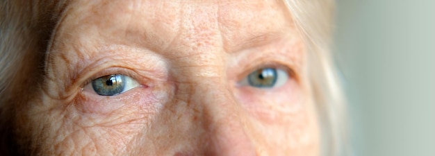 Zdjęcie smutne niebieskoszare oczy starszej kobiety patrzącej w kamerę z ekstremalnym zbliżeniem ujęcie wizji i koncepcja...