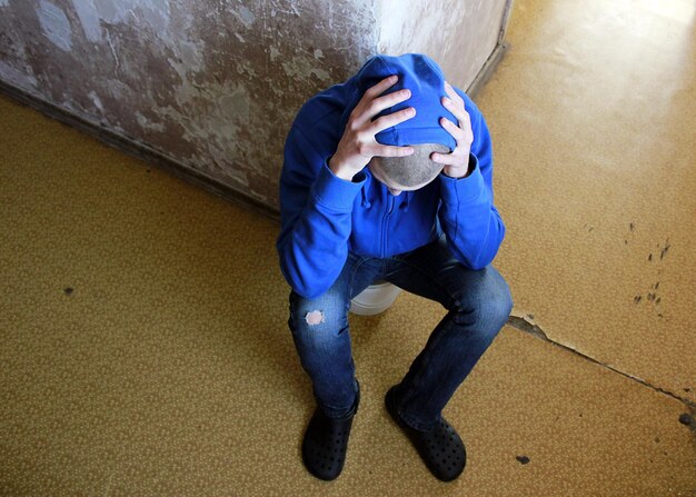 Smutny człowiek siedzący na podłodze w domu koncepcja Blue Monday