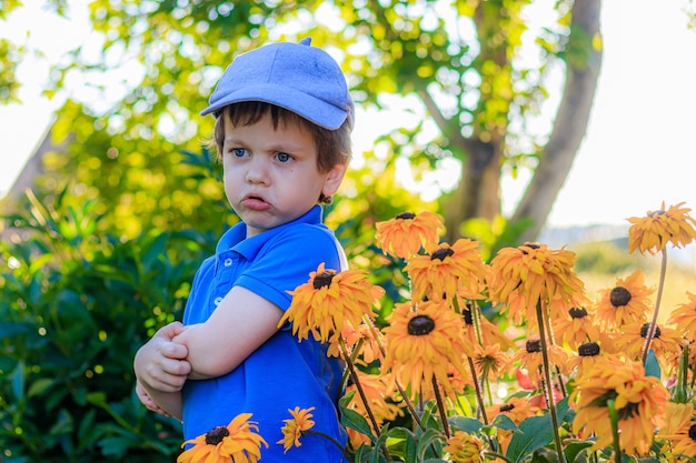 Smutny mały chłopiec ubrany na niebiesko stojący na zewnątrz