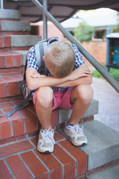 Smutny uczeń siedzi samotnie na schody