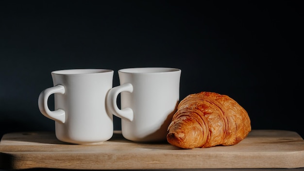 Zdjęcie Śniadanie dla dwojga dwie filiżanki gorącej herbaty i świeżego rogalika
