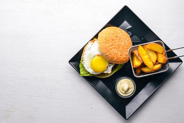 Śniadanie frytki i burger z mięsem i jajkiem Na drewnianym tle Widok z góry Wolne miejsce