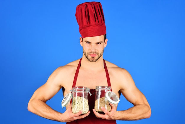 Śniadanie i zdrowa żywność seksowny męski szef kuchni z poważną twarzą w bordowym kapeluszu i fartuchu trzyma w rękach