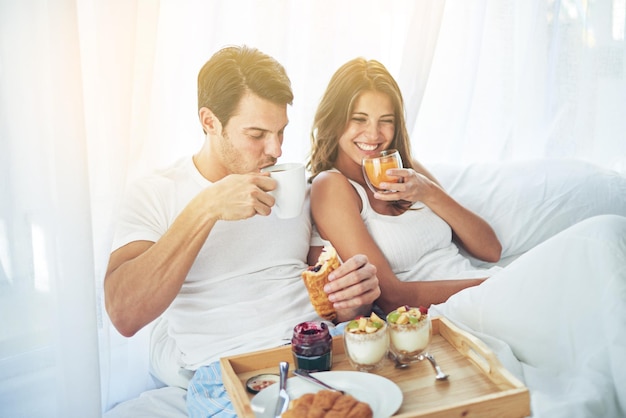 Śniadanie jest lepsze, gdy dzielisz je w łóżku Ujęcie kochającej młodej pary cieszącej się śniadaniem w łóżku?