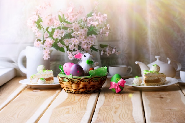 Śniadanie Lub Brunch Na Drewnianym Stole Z Easter Bunny, Kolorowymi Jajkami, Ciastem Wielkanocnym I Filiżanką Herbaty. Koncepcja Poranka Wielkanocnego.