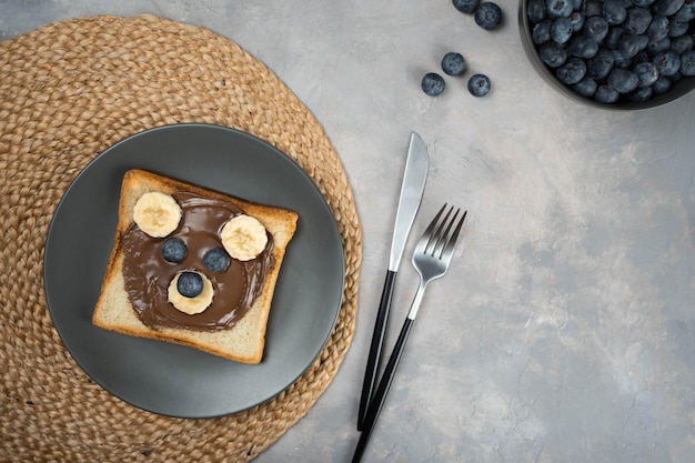 Śniadanie Lub Lunch Dla Dzieci Lub Tosty Z Przekąskami Z Kremem Czekoladowym Z Orzechami Laskowymi, Bananem I Jagodami W Kształcie Uroczego Misia.