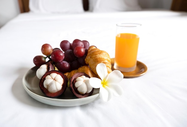 Śniadanie, owoce, rogaliki, sok pomarańczowy na białym prześcieradle, koncepcja zdrowej żywności.
