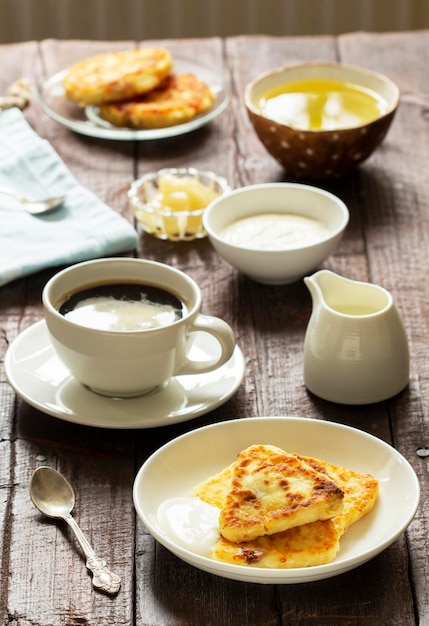 Śniadanie składające się z serników, kawy i herbaty. Serniki o nietypowym trójkątnym kształcie.