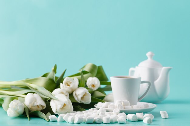 Śniadanie z filiżanką kawy i białymi tulipanami na równinie