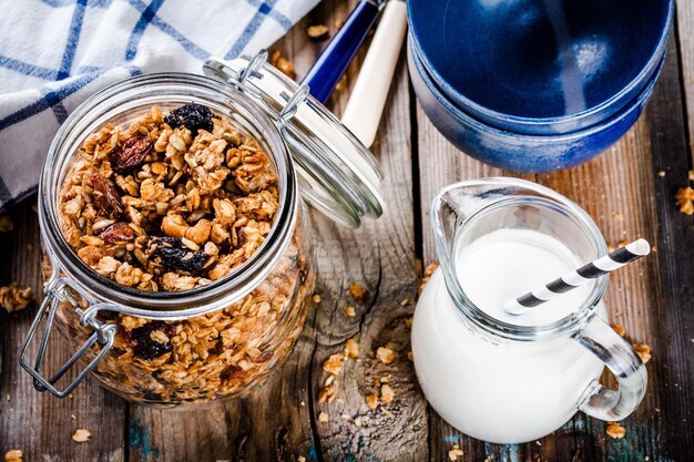 Śniadaniowa domowa granola w szklanym słoiku i dzbanek mleka