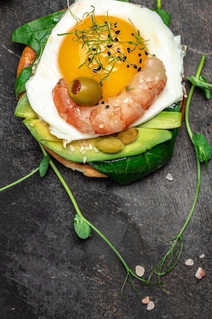 Zdjęcie Śniadaniowe sanwich z pełnoziarnistym chlebem miękkie smażone jajko szpinak awokado krewetki na ciemnym tle ketogeniczne śniadanie koncepcja pożywienia zdrowe czyste jedzenie widok z góry