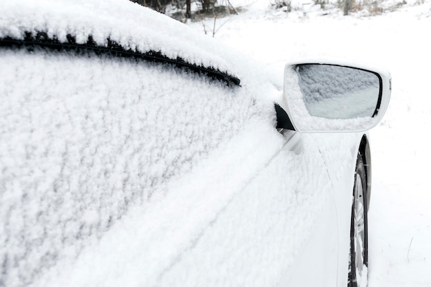 Śnieg na przedniej szybie lusterka wstecznego w miejscu parkingowym podjazdu samochodu sedan;