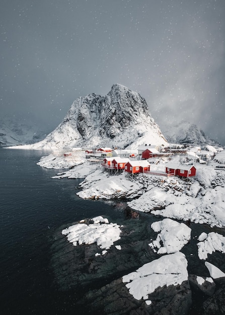 Śnieg w wiosce rybackiej Hamnoy z zaśnieżoną górą na wybrzeżu na Lofotach Norwegia
