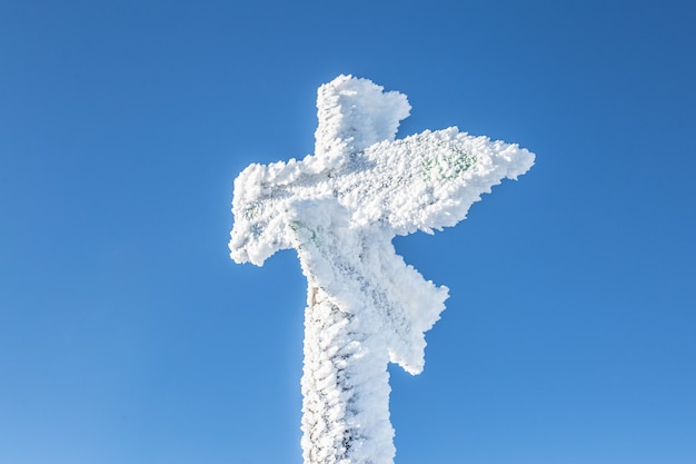 Śnieg zakrywał drewnianego kierunkowskaz w górach.