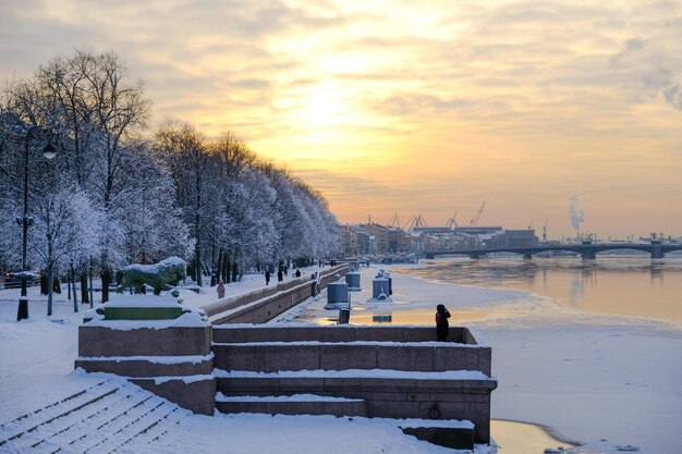 Śnieżna zimowa scena z rzeką i budynkiem na pierwszym planie.