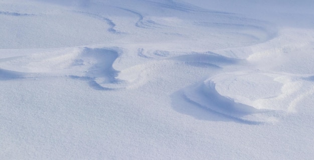 Śnieżne tło, pokryta śniegiem powierzchnia ziemi po porannej śnieżycy w słońcu z wyraźnymi warstwami śniegu