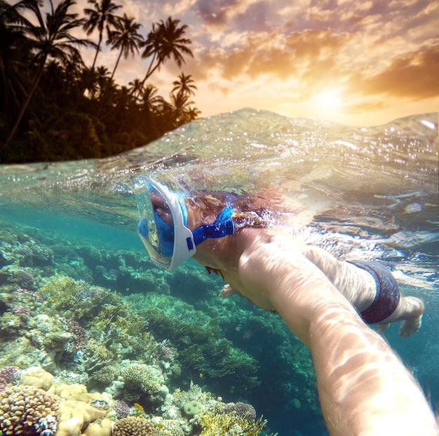 Snorkeling w pobliżu tropikalnej wyspy Młody mężczyzna pływa w wodzie Wakacje nad morzem