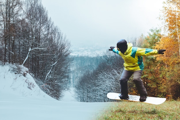 Zdjęcie snowboardzista czeka na sezon narciarski stojąc na jesiennym stoku