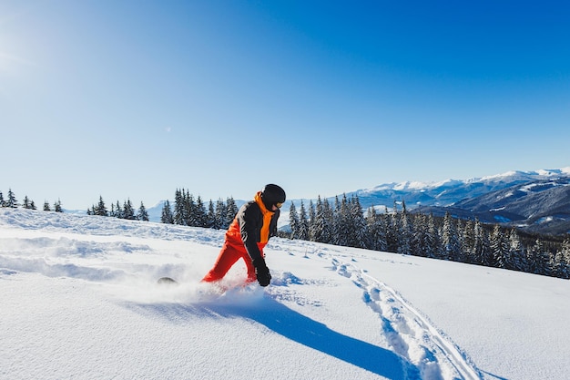 Snowboardzista idzie w dół zaśnieżonym zboczu w zimie na śniegu Freeride zimą na snowboardzie