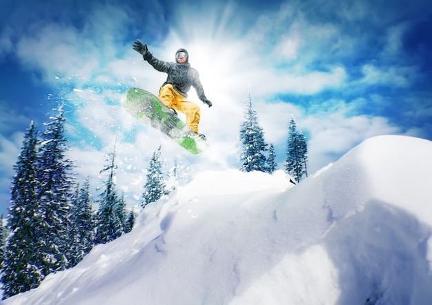 Zdjęcie snowboardzista skacze z nieba i drzew