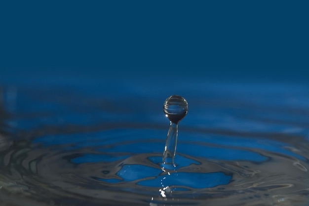 Soczysta niebieska kropelka i sznurek wody, który powstał z kropli wody
