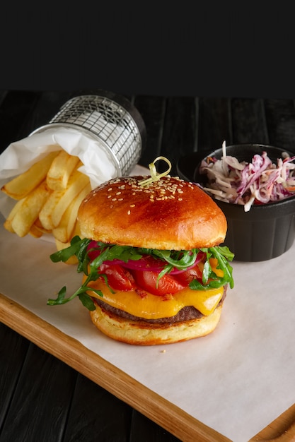 Zdjęcie soczysty burger wołowy z sosem borówkowym, topionym serem, rukolą podawany ze smażonymi ziemniakami i czerwoną kapustą