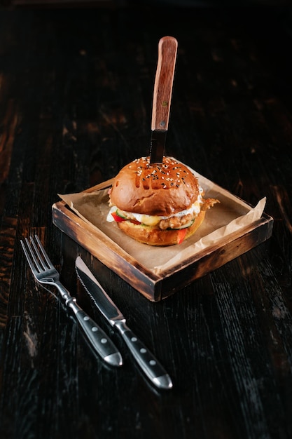 Soczysty burger wołowy z widelcem i nożem na drewnianym stole