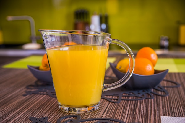 Sok pomarańczowy w dzbanku i pomarańczy. Zdrowe odżywianie, żywność, dieta i koncepcja wegetariańska. Sok pomarańczowy na drewnianym stole