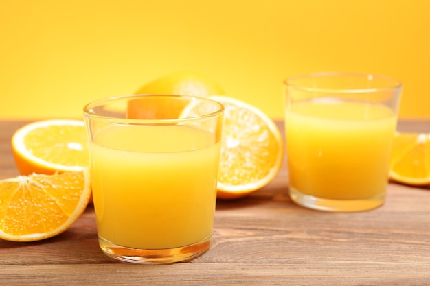 Sok pomarańczowy w szklance pomarańcze i plastry pomarańczy na stole