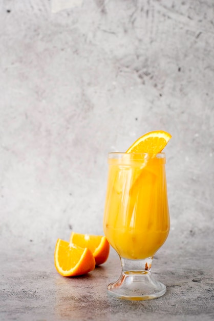 sok pomarańczowy w szklance z lodem świeże owoce na ciemnym stole