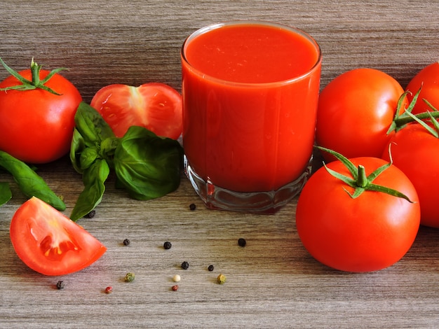 Zdjęcie sok pomidorowy, pomidory na gałęzi, bazylia, mieszanka papryki.