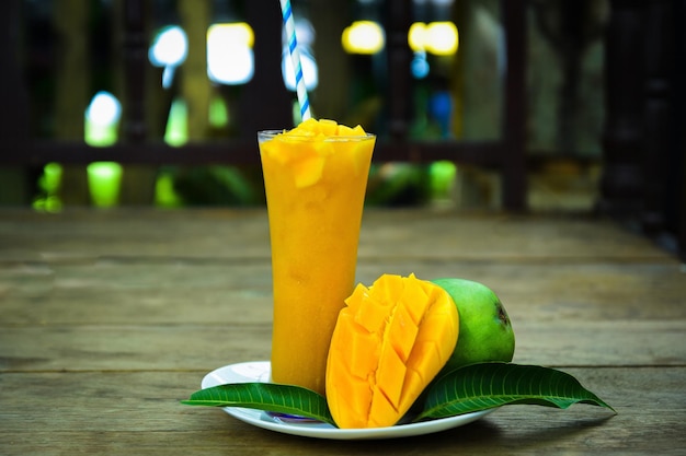 Sok z mango z plasterkiem mango na białym tle na talerzu. Szklanka soku z mango.