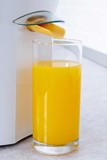 Sokowirówka ze szklanką świeżego soku pomarańczowego w nowoczesnej kuchni.