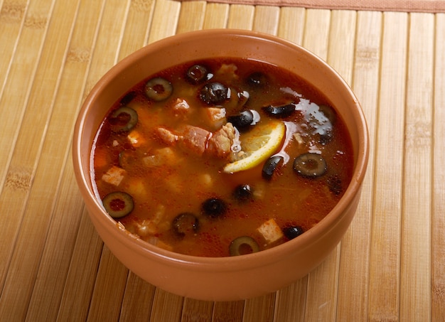 Solanka na talerzu. Solanka, zupa rosyjska z wołowiną, kiełbasą, kurczakiem i cytryną, oliwki