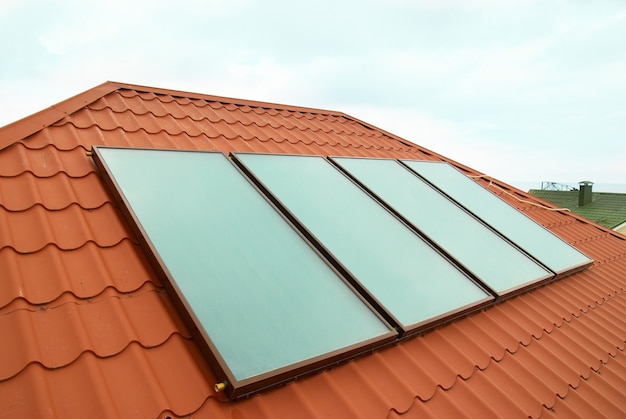 Solarny system ogrzewania wody geliosystem na czerwonym dachu domu.