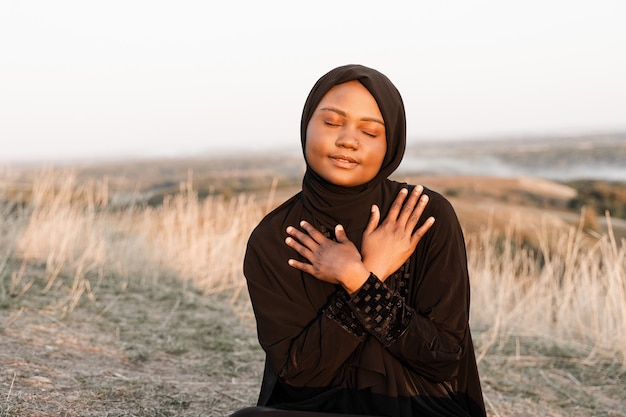 Solat tradycyjna modlitwa do boga na dywanie. Czarna muzułmanka modli się do Allaha. Tradycja narodowa Ramadanu.