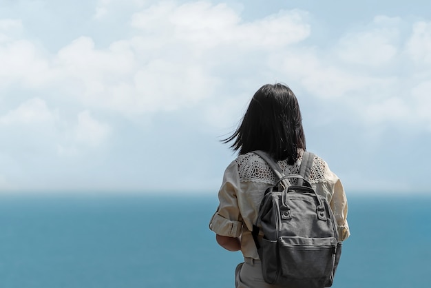 Solo Azjatycki piękny dziewczyna plecaka podróżnik stoi samotnie i patrzeje morze
