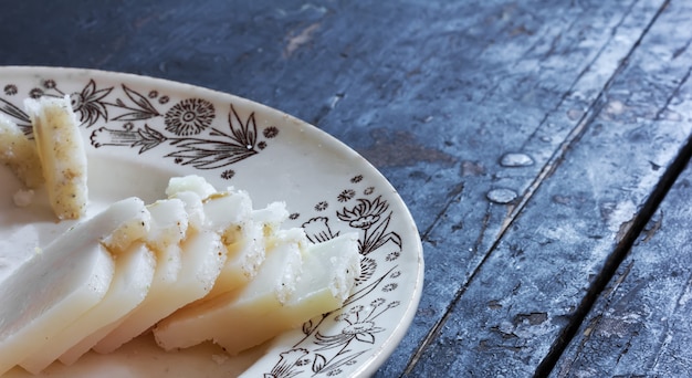 Solony tłuszcz wieprzowy pokroić na małe kawałki na ceramicznym talerzu na starym czarnym drewnianym stole
