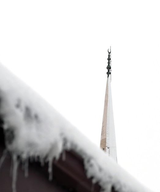 Sople na dachu pada śnieg, sroga zima minaret meczetu i sroga zima w Turcji